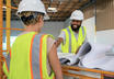 Two people reviewing plans at a construction site