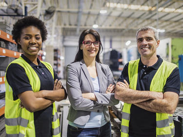 Three members of a warehouse team smiling at the camera
