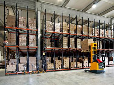 Forklift placing product on a rack in a warehouse.