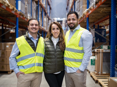 Three members in a warehouse team smiling at the camera