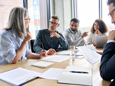 People sitting around a large table in an office People sitting around a large table in an office