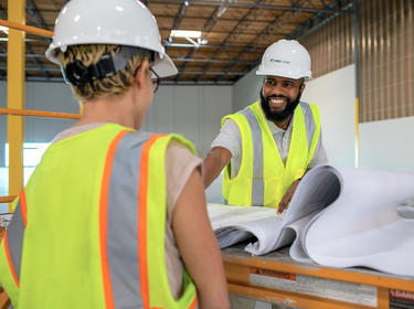 Two people reviewing plans at a construction site